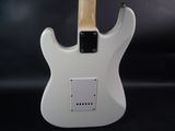 a close up of a white electric guitar on a black background