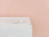 une paire de boucles d'oreilles à clous en diamant posée sur un bloc de marbre