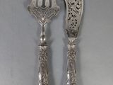 pair of silver plated utensils with ornate designs on them