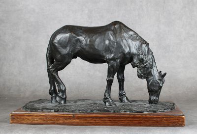 statue d'un cheval posée sur un socle en bois, sur fond gris