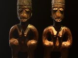 deux statues en bois représentant deux hommes, posées sur une table en bois
