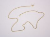 un gros plan d'un collier avec une chaîne en or posé sur une surface blanche