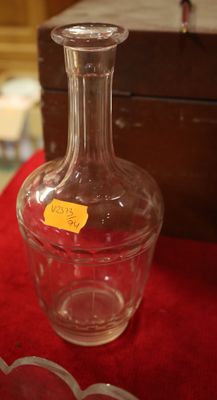 une bouteille en verre posée sur une table, avec une boîte en arrière-plan
