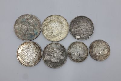 six types différents de pièces d'argent sur une surface blanche