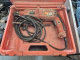 une boîte à outils rouge contenant un cordon et une perceuse