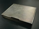 a silver cigarette case on a table with a black background
