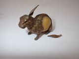 a small bronze rabbit figurine sitting on a white surface