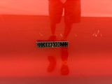 a reflection of a man standing in front of a red car