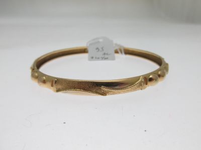 gros plan d'un bracelet en or sur une surface blanche