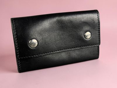 a close up of a black leather wallet on a pink background