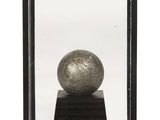 a silver ball in a glass case on a wooden stand