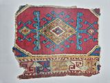 an old red and blue rug with a diamond design on it
