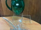 un pichet en verre vert posé sur une table en bois
