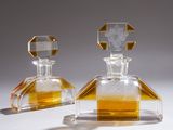 une paire de flacons de parfum en verre transparent et jaune posés sur une surface blanche