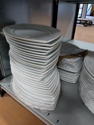 beaucoup d'assiettes empilées sur une étagère dans la cuisine