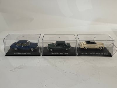 trois voitures miniatures sont exposées dans une vitrine posée sur une surface blanche