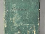 an old book with a green cover sitting on top of a table
