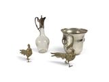 un vase en argent, un oiseau et une figurine d'oiseau sur fond blanc