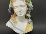 a ceramic bust of a woman with grapes on her head