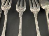 five silver spoons and a fork on a black table