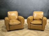 deux fauteuils en cuir marron posés sur un parquet en bois massif
