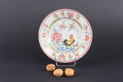 une assiette sur laquelle est représenté un coq, à côté de noix