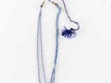 un collier de perles bleues orné d'un pompon, sur fond blanc