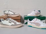 trois paires de baskets blanches et grises posées sur des cartons