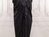a black dress on a mannequin stand in front of a white wall