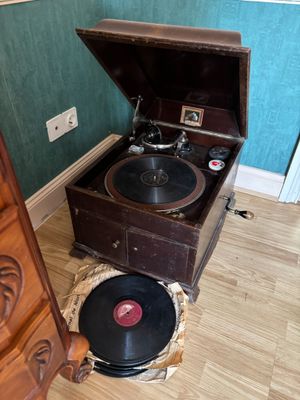 un vieux tourne-disque posé par terre à côté d'une commode