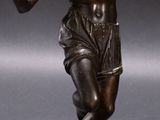 bronze statue of a man holding a tennis racket on a gray surface