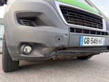 a grey van parked in a parking lot with a green sign on the front of it