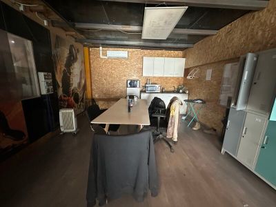 une longue table au milieu d'une pièce, avec des chaises et un réfrigérateur