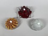 three small glass objects are sitting on a white surface