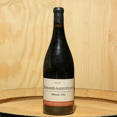 a bottle of wine sitting on top of a wooden barrel