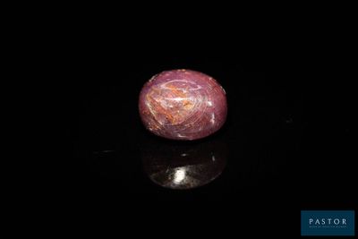 un gros plan d'une bille en marbre rose posée sur une surface noire