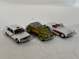 three toy cars sitting next to each other on a white surface