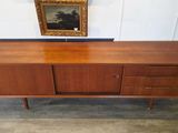 an image of a wooden sideboard with a painting on the wall
