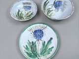 three pieces of blue and white pottery with thistle designs on them