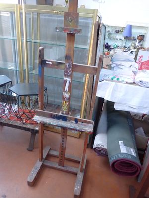 an easel with a glass case and a chair in the room