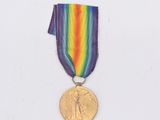 une médaille d'or entourée d'un ruban aux couleurs de l'arc-en-ciel