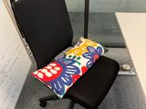 a chair that has a pillow on it in front of a whiteboard