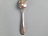 silver spoon on a white plate with a yellow dot on it