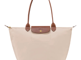 Le sac Longchamp est muni d'une poignée en cuir et est de couleur beige et marron.