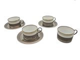 quatre tasses à café et leurs soucoupes posées sur une soucoupe, sur une surface blanche