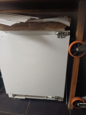 a small white refrigerator in the corner of a room