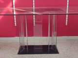 a glass table with a black base and a red wall in the background