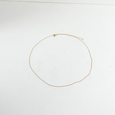 un collier en or orné d'une étoile, posé sur une surface blanche