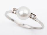 a close up of a pearl and diamond ring on a white background