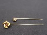 a pair of gold tone hair pins with a red stone